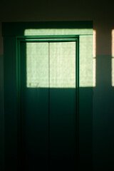 sunlight shines through the window onto the door of the elevia of an apartment building.