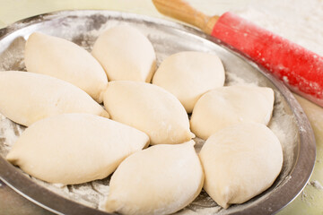 Raw pies on metal tray. Baking buns on a baking tray.