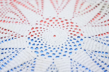abstract white knitted floral lace on a  blue and red background creating a beautiful textured background with space to write your text 