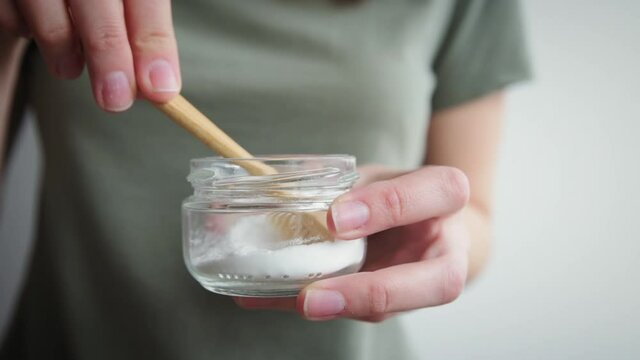Woman holds bamboo toothbrush and soda powder in her hands