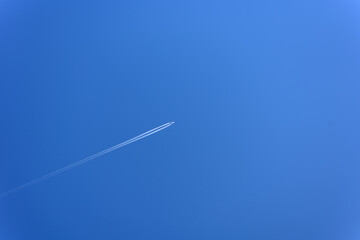The plane is flying high in the blue clear sky