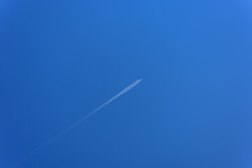 The plane is flying high in the blue clear sky