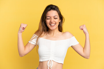 Young caucasian woman isolated on yellow background doing strong gesture