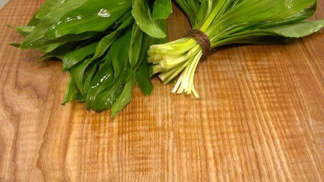 Wild garlic leaves on a wooden cutting board.