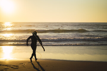 Silhouette of a surfer running to the water at sunset