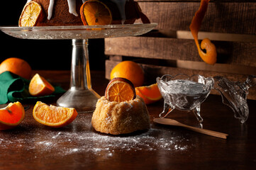 orange cake with glass foot white icing drizzled with dried orange slices sugar bowl natural oranges dark food