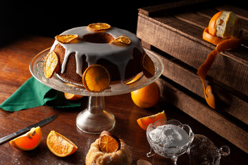 orange cake with glass foot white icing drizzled with dried orange slices sugar bowl natural oranges dark food