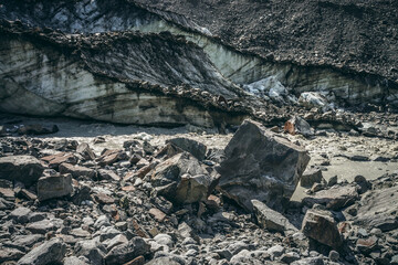Scenic landscape of mountain river beginning from glacier with large moraines and ice chunks. Beautiful scenery with glacier at source of glacial river. Mountain river among big stones and ice blocks.