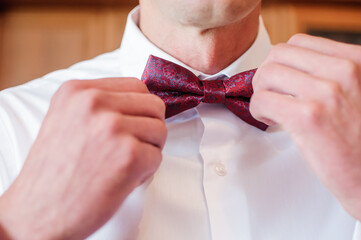 Red bow tie in the hands of the groom. Bow tie in the hands of a man