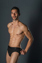 Fototapeta na wymiar Fashion close-up portrait of a handsome male with bare torso posing in black underwear on isolated background