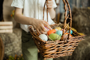 Fototapeta na wymiar close-up of a child's hand picking out colorful eggs in a wicker basket. Easter Holiday