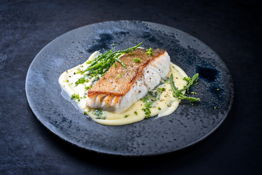 Modern style traditional fried skrei cod fish filet with mashed potatoes and glasswort served as top view on ceramic design plate with copy space