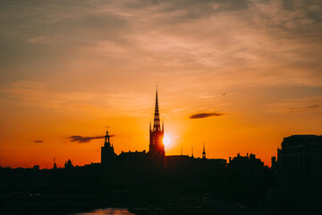 Stockholm, Sweden. Sunset Sun Shine Through Dark Silhouette Of Riddarholm Church In Stockholm Skyline. Scenic View Of Gamla Stan Old Town In Dramatic Sunshine Sunlight. Popular Destination Scenic