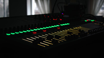 Dj's Mixing console with bright buttons make music on dark background