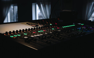 Dj's Mixing console with bright buttons make music on dark background