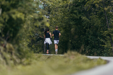 Fototapeta na wymiar Young fit couple atheltes running on running road in a forest.