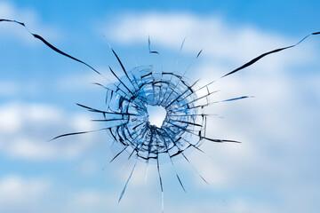 Fototapeta premium Cracks in the window glass on a background of sky.