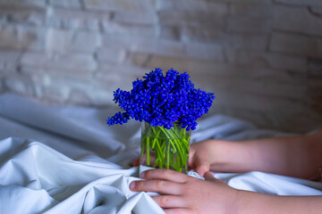 a vase bouquet of flowers in the hands of  a little girl muscari