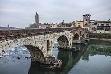 Obraz premium View of Stone Bridge (Ponte Pietra or Pons Marmoreus) - Roman arch bridge crossing the Adige River in Verona, Italy. The bridge completed in 100 BC, is the oldest bridge in Verona.