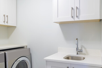 An empty laundry room with cabinet, sink, washer and drier.