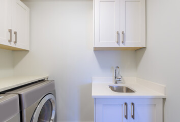 An empty laundry room with cabinet, sink, washer and drier.