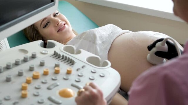 The doctor uses ultrasound equipment when examining a pregnant woman. A professional female obstetrician-gynecologist conducts a prenatal examination of the expectant mother in a hospital.