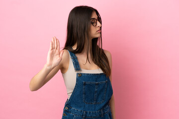 Young caucasian woman isolated on pink background making stop gesture and disappointed