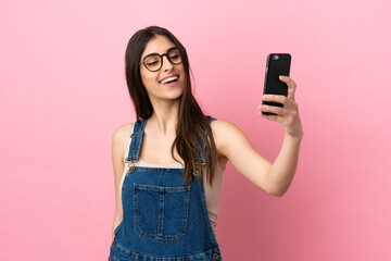 Young caucasian woman isolated on pink background making a selfie