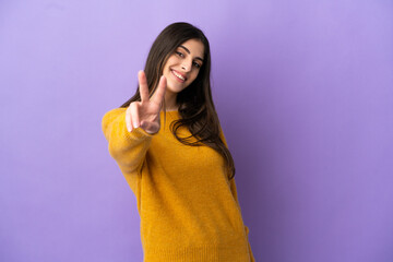 Young caucasian woman isolated on purple background smiling and showing victory sign