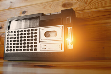 Old cassette tape recorder on wooden background.