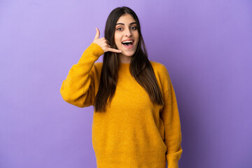 Young caucasian woman isolated on purple background making phone gesture. Call me back sign