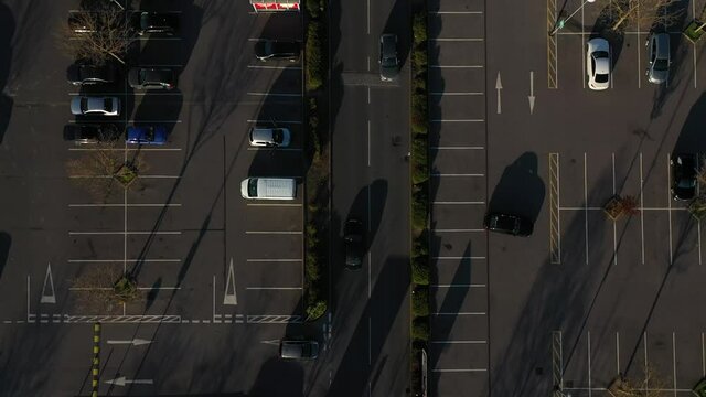 top down tracking of a black car leaving parking lot with lots of cars