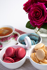 Different types of colorful macaroons with a Cup of hot tea on white background Decorated with flowers Vintage style