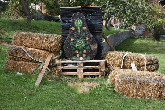 Traditional arrow target board with arrows stuck on it near haystack on farm. Target board for shooting arrows