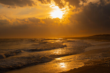 sunset on the beach with warm reflections hitting the sand after water receded long island new york high tide