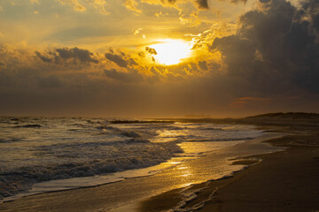 sunset on the beach with warm reflections hitting the sand after water receded long island new york high tide