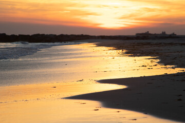 sunset on the beach with warm reflections hitting the sand after water receded long island new york