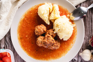 Top view on meat balls in a plate with tomato sauce and mashed potatoes on wooden rustic table - homemade food healthy eating traditional meal copy space