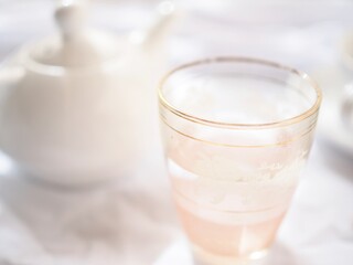 Pretty pink glass and white teapot on a bright white background.