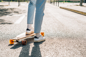 close-up take of the legs of an unrecognizable man on a skateboard on the street asphalt. He is projecting a hard shadow on the asphalt.