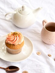 Pretty pink cupcake, pink mug and white teapot on a white pretty background