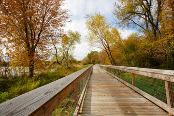 Fototapeta na wymiar Walking trail on a wood bridge that seems to go forever over the wetlands in autumn