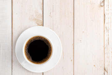 A cup of coffee in top view placed on white pine wood table top at an intersection point with copy space for placing anything. Texture background concept.