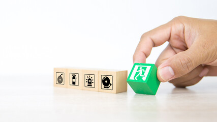 Fire exit,  Close-up hand choose wooden toy block stack with door exit sing or fire escape icon...