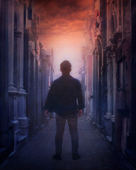 A man in an old cemetery path with a light at the orange sky. Death concept. Passing away concept.
