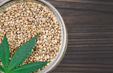 Cannabis seeds in glass bowl on dark table with copy space