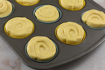 Raw swirl corn muffin dough in silicone muffin cups in muffin pan