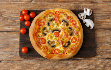 Pizza with tomatoes, mozzarella, salami, mushrooms on wooden table