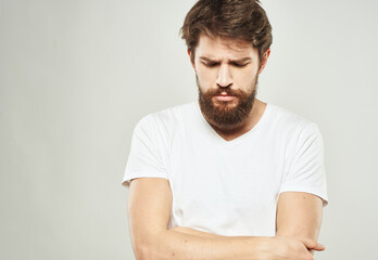 Obraz premium a man with a puzzled look looks to the side on a light background and a thick beard