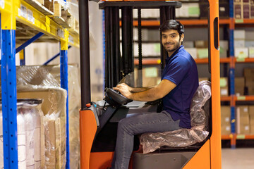 Fototapeta na wymiar Male warehouse worker driving and operating on forklift truck for transfer products or parcel goods in the industrial storage factory warehouse